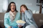 two-best-friends-sitting-on-sofa-eating-popcorn-watching-mo[...]